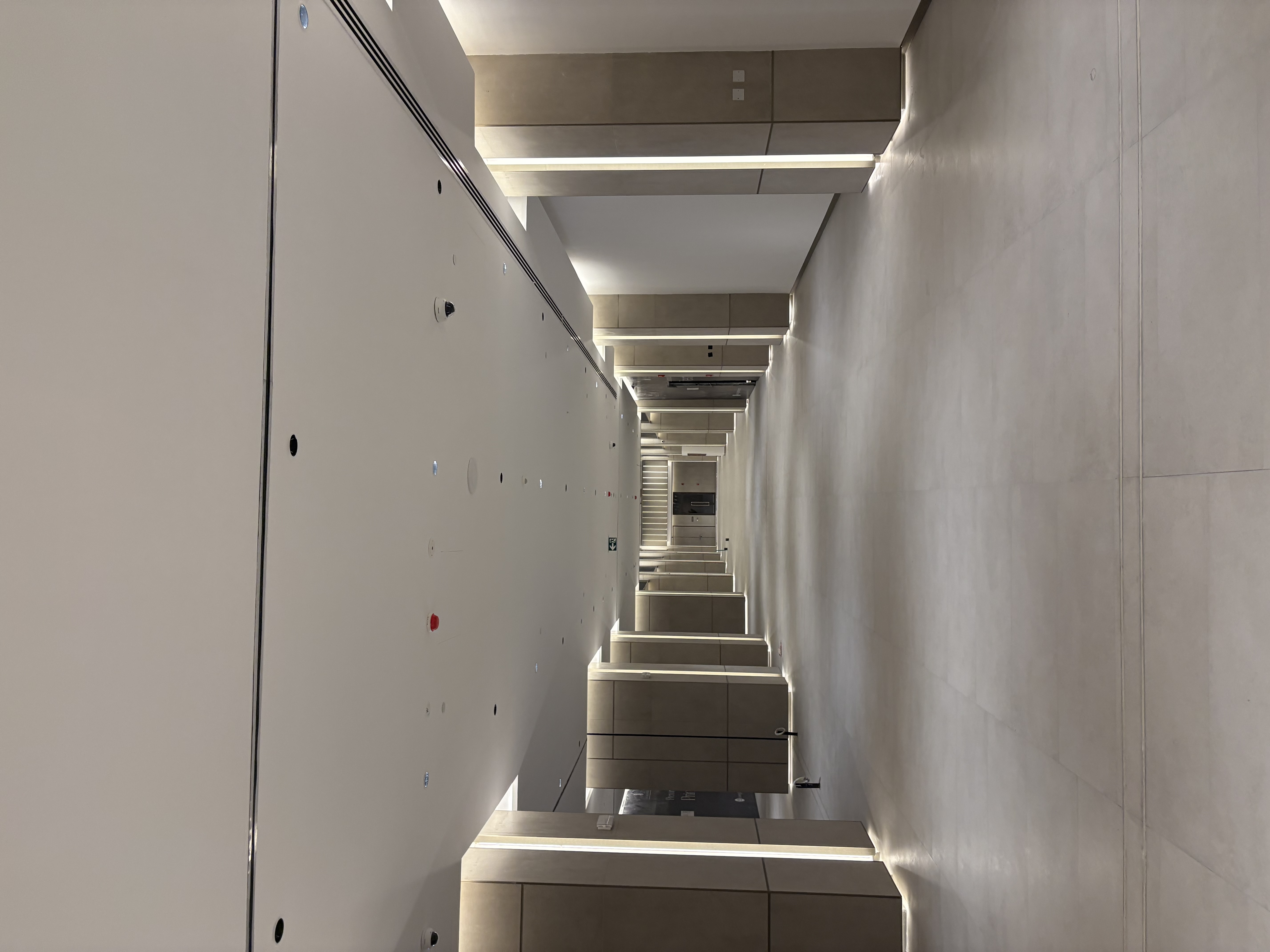 Long elegant corridor inside the Biltmore Commercial Tower with recessed ceiling lighting and illuminated vertical wall panels
