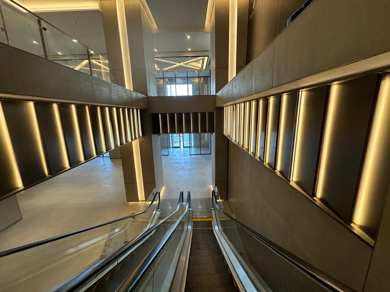 Escalators inside the Biltmore Commercial Tower lobby with warm vertical lighting and modern architectural finishes