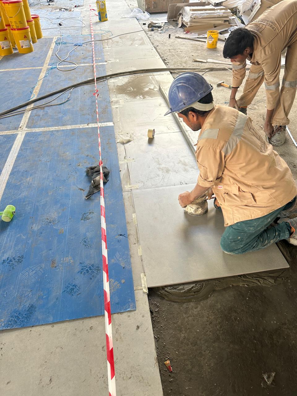 SpaceForge tiling team laying large-format stone floor tiles on a luxury fit-out project in Dubai