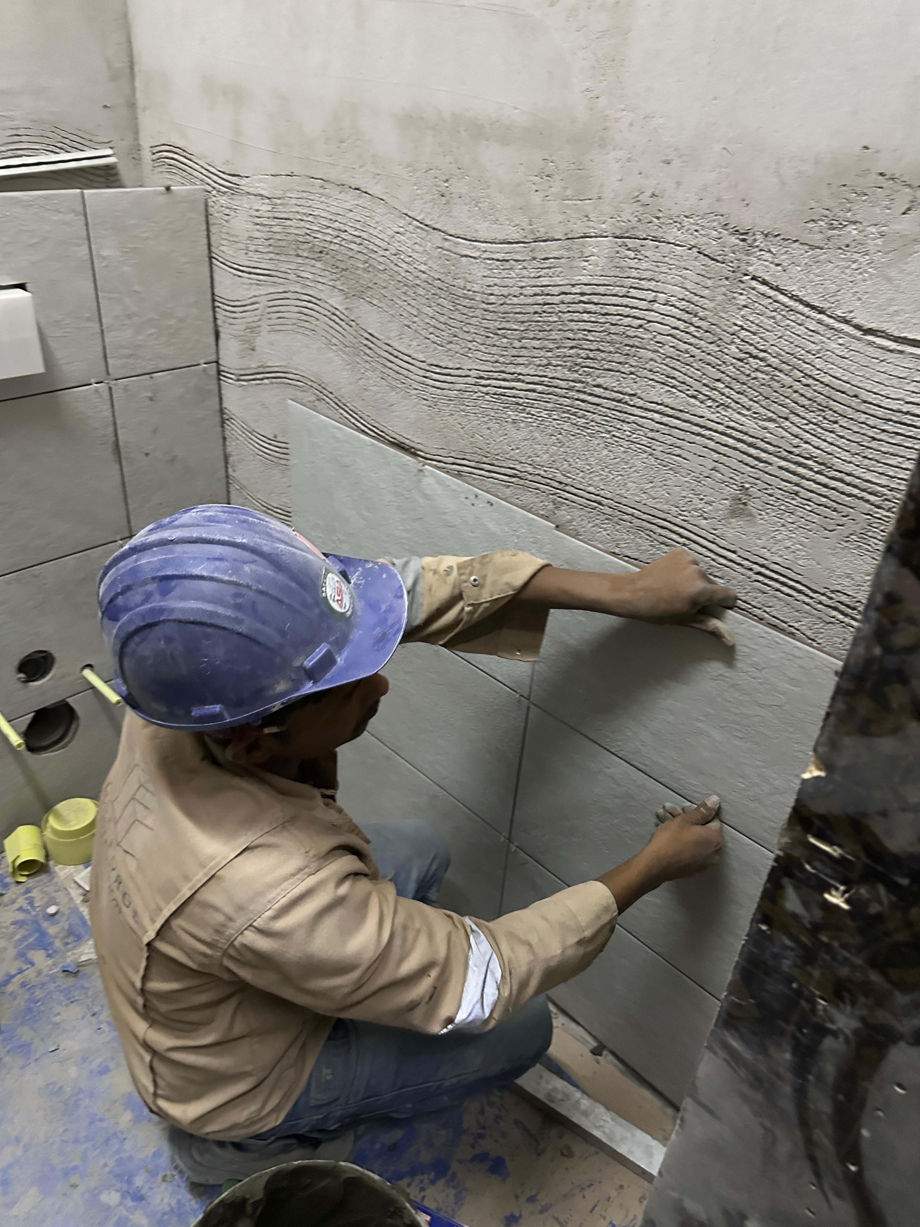 SpaceForge craftsman applying adhesive mortar for precision wall tiling on a luxury residential fit-out project in Dubai