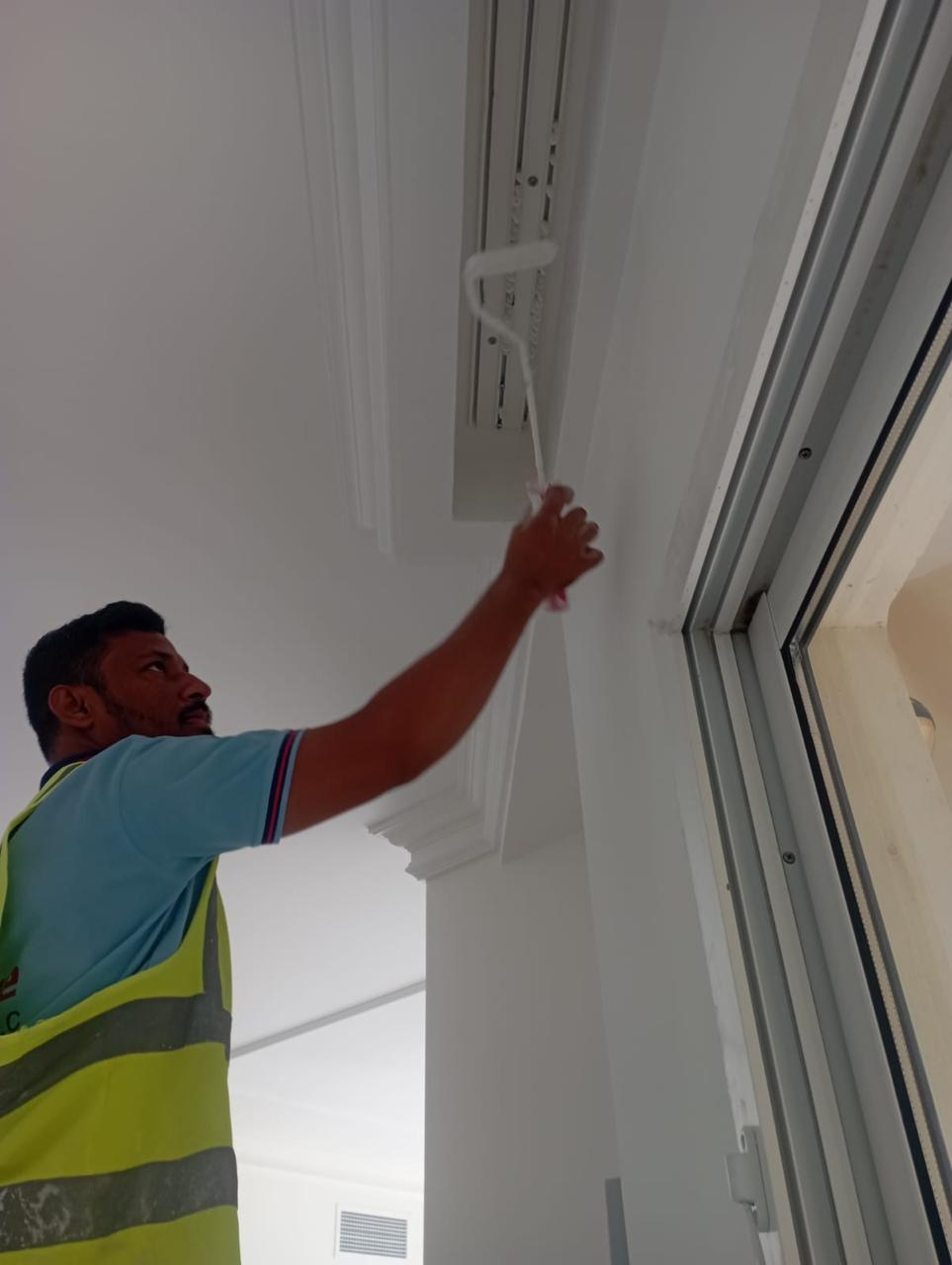 SpaceForge fit-out craftsmanship Dubai, worker installing bespoke ceiling cornice and window trim detail on a luxury residential project