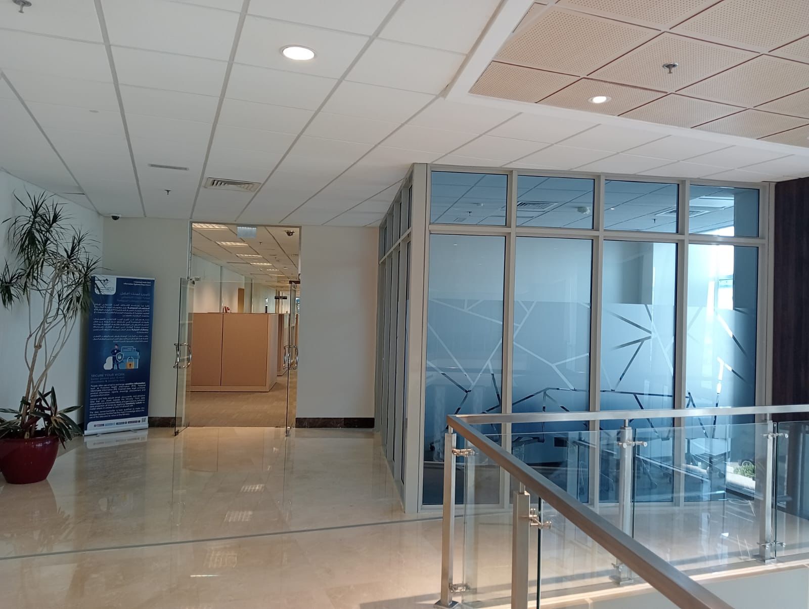 SpaceForge commercial fit-out Dubai, finished office corridor with glass-enclosed staircase and polished tile flooring