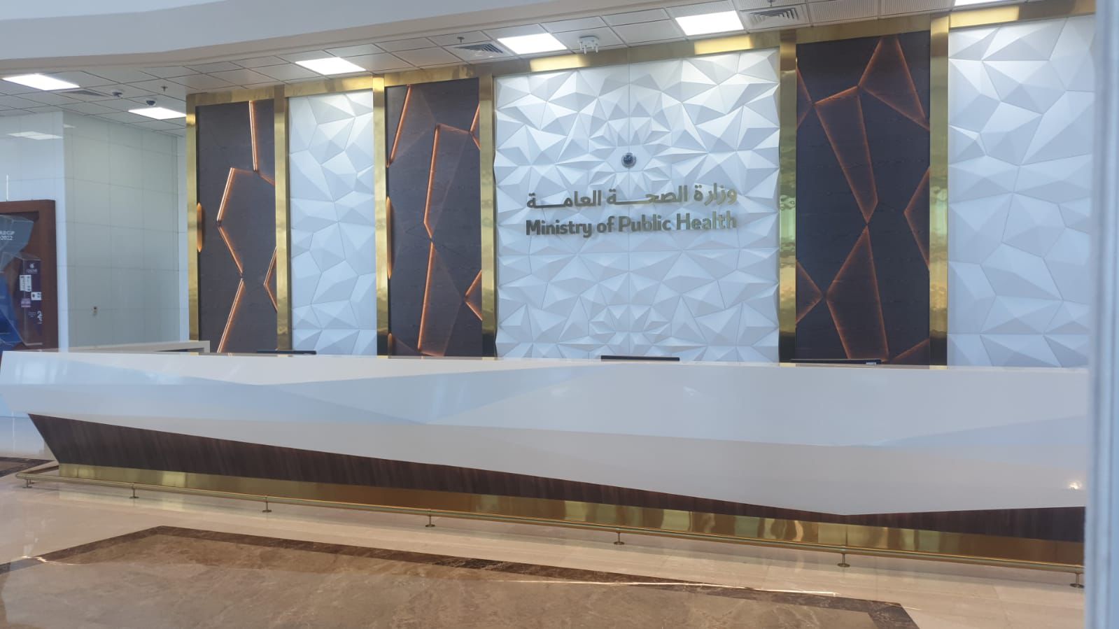 SpaceForge commercial interior fit-out Dubai, completed reception desk with illuminated marble wall cladding, decorative columns, and bespoke Arabic signage